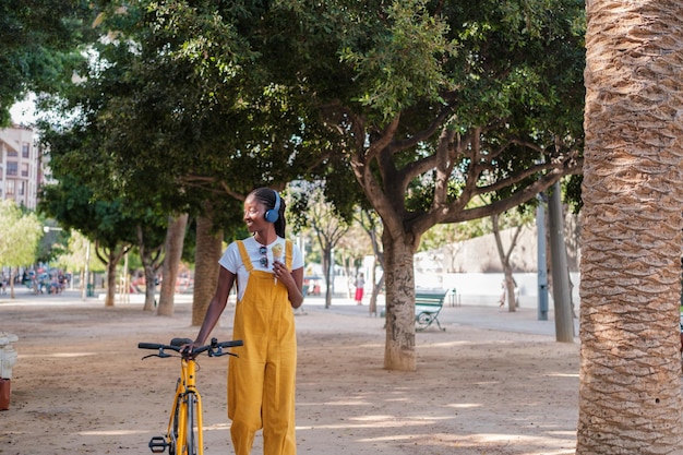 Junge Frau geht durch die Stadt, isst Eis und fährt auf ihrem Concept-Lifestyle-Fahrrad gelb