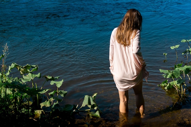 Junge Frau geht in einem Hemd zum Baden in den Fluss