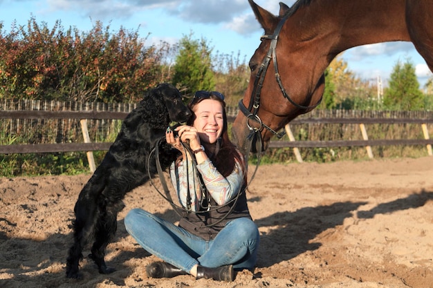 Junge Frau genießt Geselligkeit mit einem schwarzen Hund und einem braunen Pferd