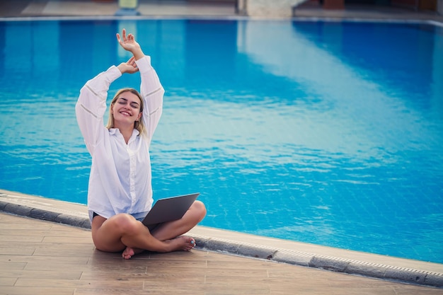 Junge Frau Geschäftsmann mit Laptop sitzt am Pool Offener Arbeitsplatz Freelancer-Konzept Online-Shopping Urlaubsarbeit