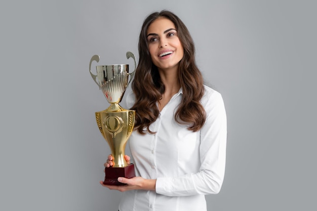 Junge Frau glücklich mit einem Champion-Cup auf grauem Hintergrund Porträt der jungen Frau mit Gold-Trophäen-Cup