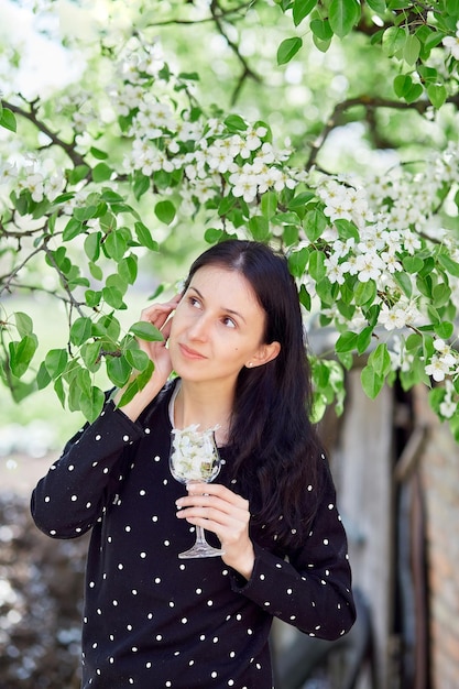 Junge Frau hält ein Glas voller Blumen, die spirituelle Atemmeditation außerhalb des Konzepts praktizieren Verbindung mit der Natur Blühender Baum Frühlingsvibes Ästhetik