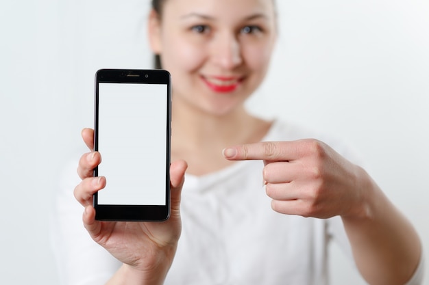 junge Frau hält ein Smartphone mit einem weißen Bildschirm vor sich und zeigt mit dem Finger darauf