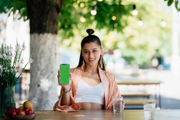 Junge Frau hält ein Smartphone mit grünem Bildschirm