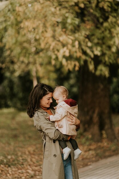 Junge Frau hält ein süßes Baby im Herbstpark