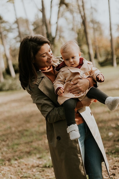 Junge Frau hält ein süßes Baby im Herbstpark