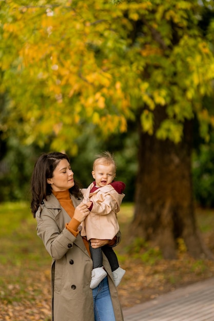 Junge Frau hält ein süßes Baby im Herbstpark