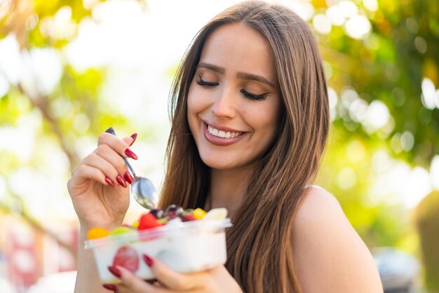 Junge Frau hält eine Schale Obst im Freien