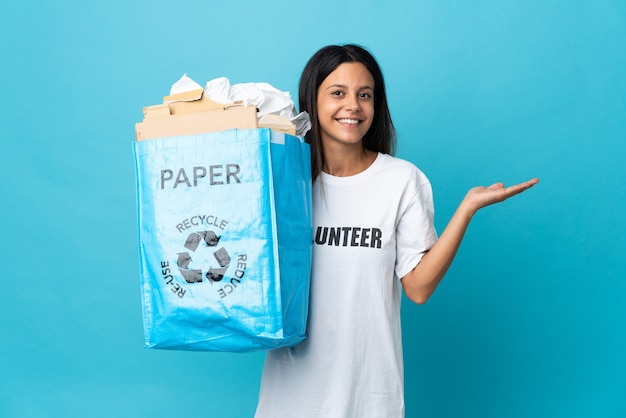 Junge Frau hält einen Recyclingbeutel voll Papier, der Hände zur Seite ausstreckt, um einzuladen, zu kommen