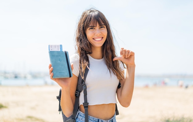 Junge Frau hält stolz und selbstzufrieden einen Reisepass im Freien in der Hand