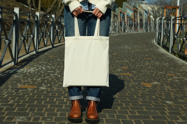 Foto junge frau halten leere öko-tasche im freien