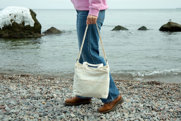 Junge Frau halten stilvolle Öko-Tasche am Kieselstrand