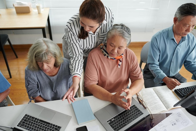 Foto junge frau hilft verwirrten älteren frauen, programm auf laptops zu starten