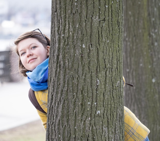 Junge Frau hinter Baum