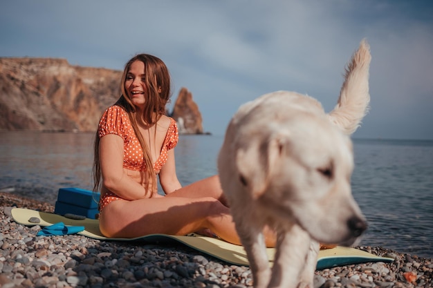 Junge Frau im Badeanzug mit langen Haaren, die das Dehnen im Freien auf einer Yogamatte am Meer auf a praktiziert