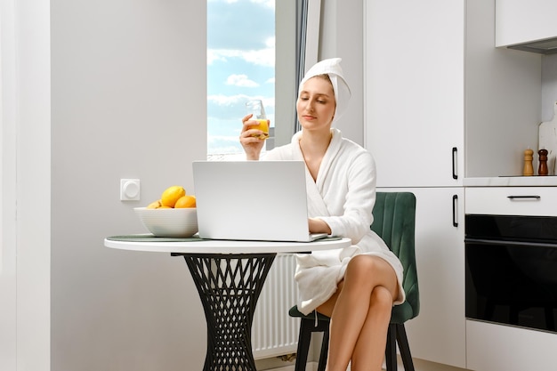 Junge Frau im Bademantel checkt beim Frühstück ihre Post