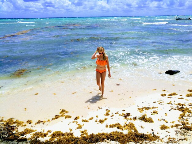 Foto junge frau im bikini geht an einem sonnigen tag am meer.