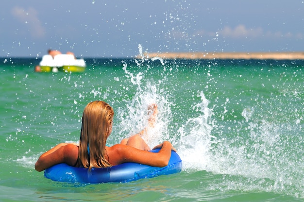 Foto junge frau im bikini rückwärts im meerwasser auf schwimmkreis