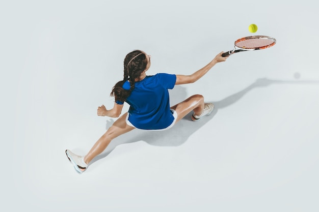 Junge Frau im blauen Hemd, die Tennis spielt. Jugend, Flexibilität, Kraft und Energie.
