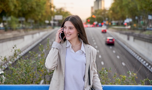 Junge Frau im Blazer, die am Handy spricht