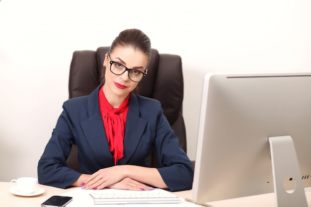 Junge frau im büro, das an dem desktop arbeitet