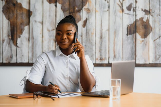 Junge Frau im Büro, die am Telefon spricht