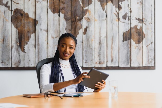 Junge Frau im Büro, die an einer Tablette arbeitet