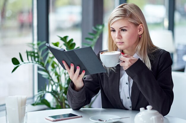 Junge Frau im Café, das ein ebook liest und Kaffee trinkt