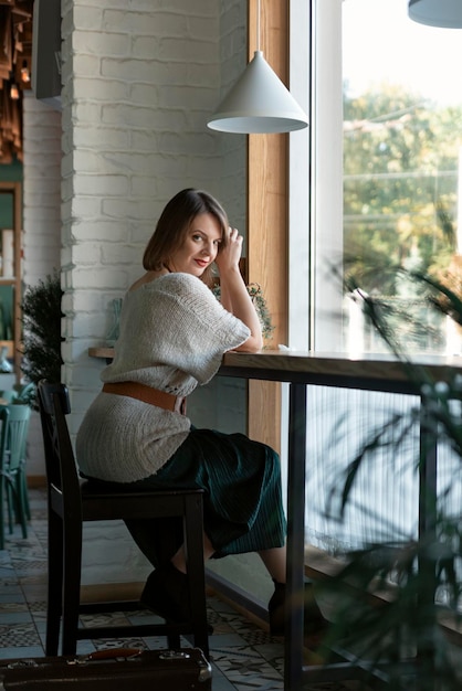 Junge Frau im Café sitzt am Tisch in der Nähe des Fensters und schaut in die Kamera Porträt einer Frau mittleren Alters in einem gemütlichen Café