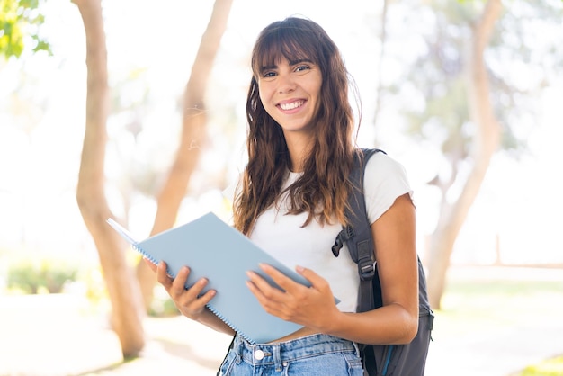 Junge Frau im Freien hält ein Notizbuch in der Hand