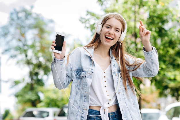 junge Frau im Freien Musik über Kopfhörer hören