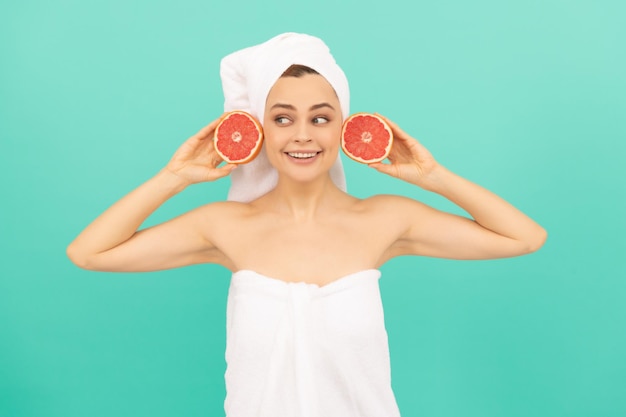 Junge Frau im Handtuch nach der Dusche mit Grapefruit auf blauem Hintergrund Kosmetologie