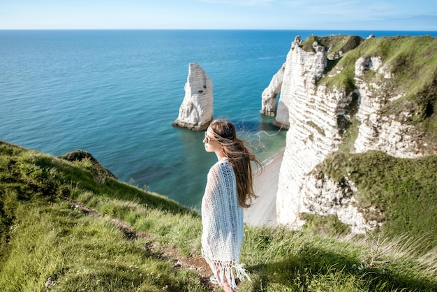 Junge Frau im Hippie-Stil, die die Natur an der felsigen Küste mit herrlichem Blick auf das Meer in Frankreich genießt