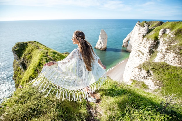 Junge Frau im Hippie-Stil, die die Natur an der felsigen Küste mit herrlichem Blick auf das Meer in Frankreich genießt