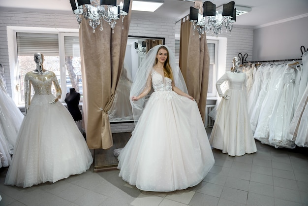 Foto junge frau im hochzeitskleid und schleier im brautgeschäft