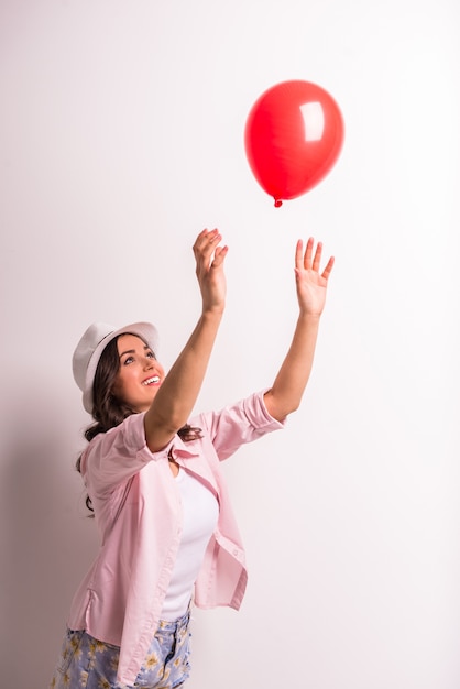 Junge Frau im Hut mit rotem Ballon.