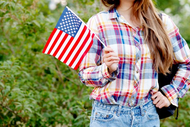 Junge Frau im karierten Hemd und in den kurzen Hosen, die amerikanische Flagge halten