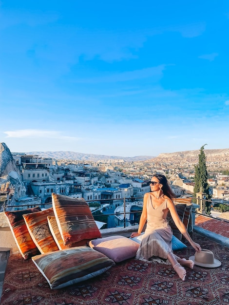 Junge Frau im Kleid auf dem Dach mit herrlichem Blick auf Kappadokien in der Türkei