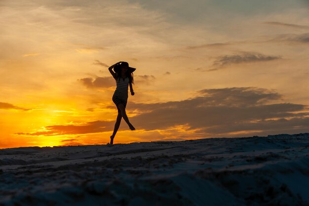 Junge Frau im Kleid, das bei Sonnenuntergang springt