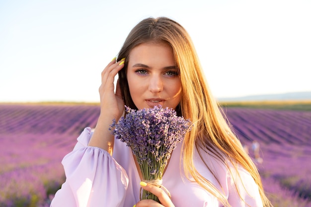 Junge Frau im Kleid mit Blumenstrauß im Lavendelfeld