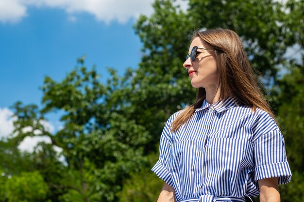 Junge Frau im Kleid und in der Brille steht im Park.