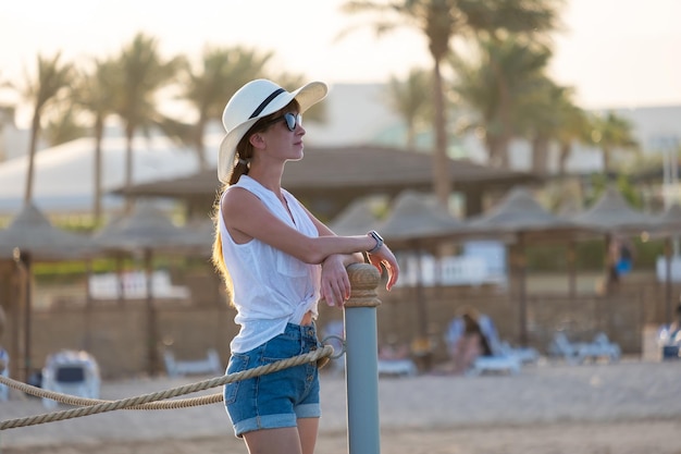 Junge Frau im lässigen Outfit, die sich an einem warmen Abend am Meer entspannt. Sommerferien und Reisekonzept.