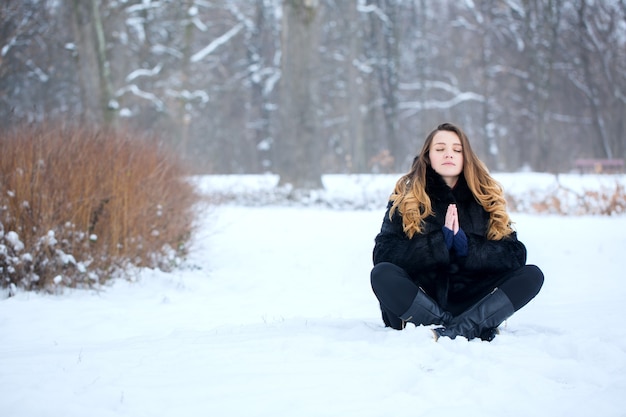 Foto junge frau im lotussitz im schnee