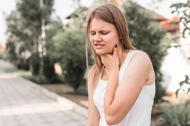 Foto junge frau im park, der nackenschmerzen hat