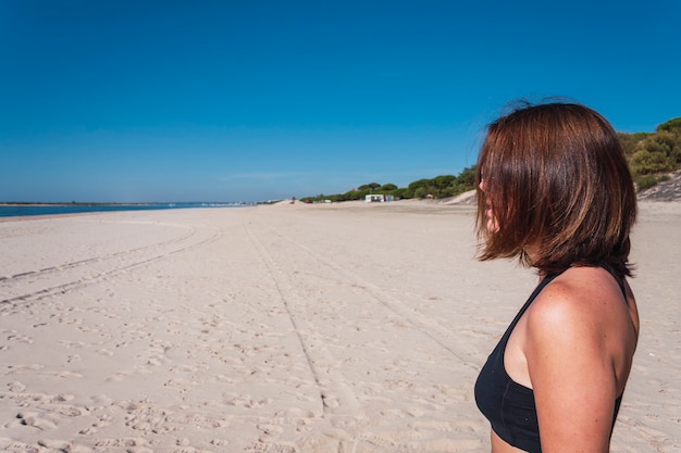 Junge Frau im Profil mit schwarzem Oberteil am Strand