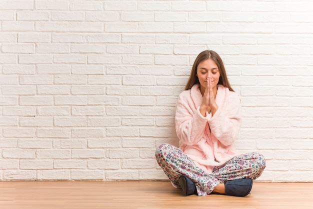 Junge Frau im Pyjama, die sehr glücklich und selbstbewusst betet