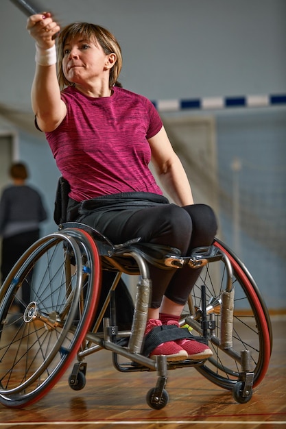 Junge Frau im Rollstuhl, die auf dem Tennisplatz Tennis spielt.
