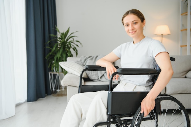 Junge Frau im Rollstuhl zu Hause im Wohnzimmer