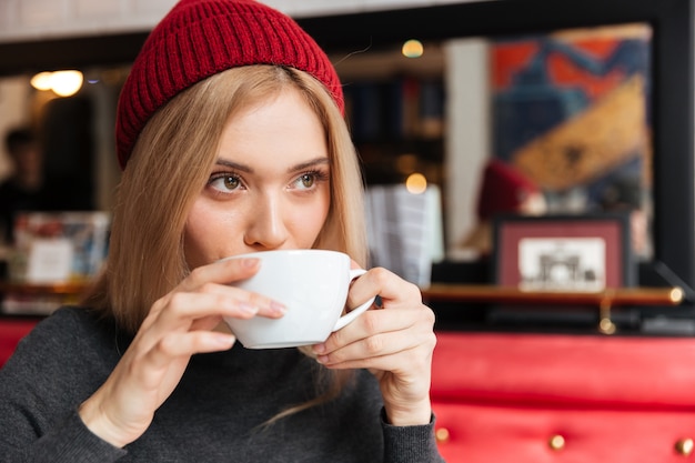 Junge Frau im roten Hut, der Kaffee trinkt