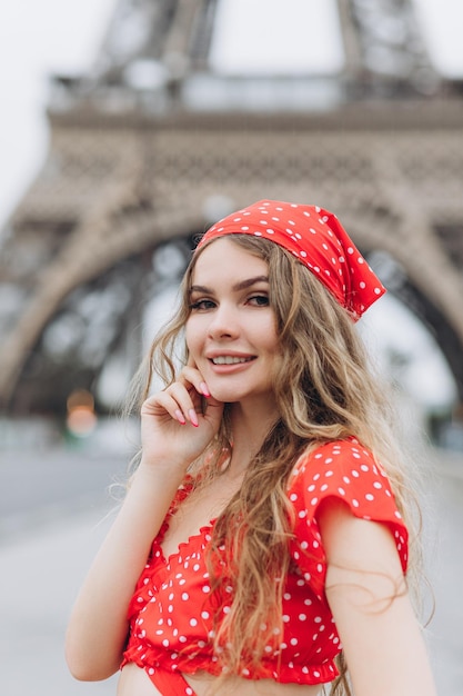 Junge Frau im roten Kleid in der Nähe des Eiffelturms in Paris an einem sonnigen Sommertag